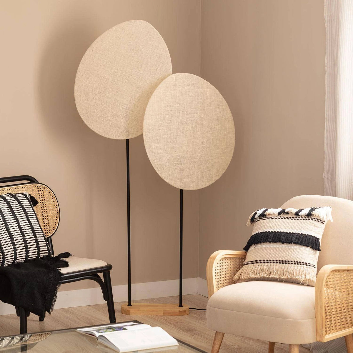 Lampadaire métal et textile ovale mis en scène dans un salon chaleureux avec fauteuils en rotin